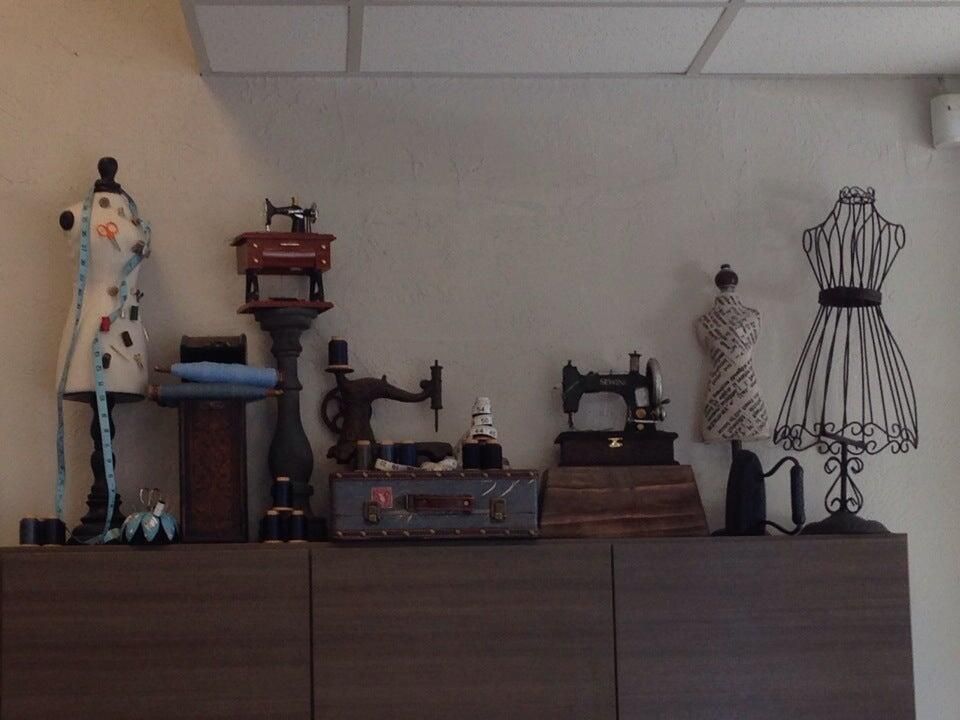 Vintage sewing machines, an antique iron and dress forms displayed on a shelf